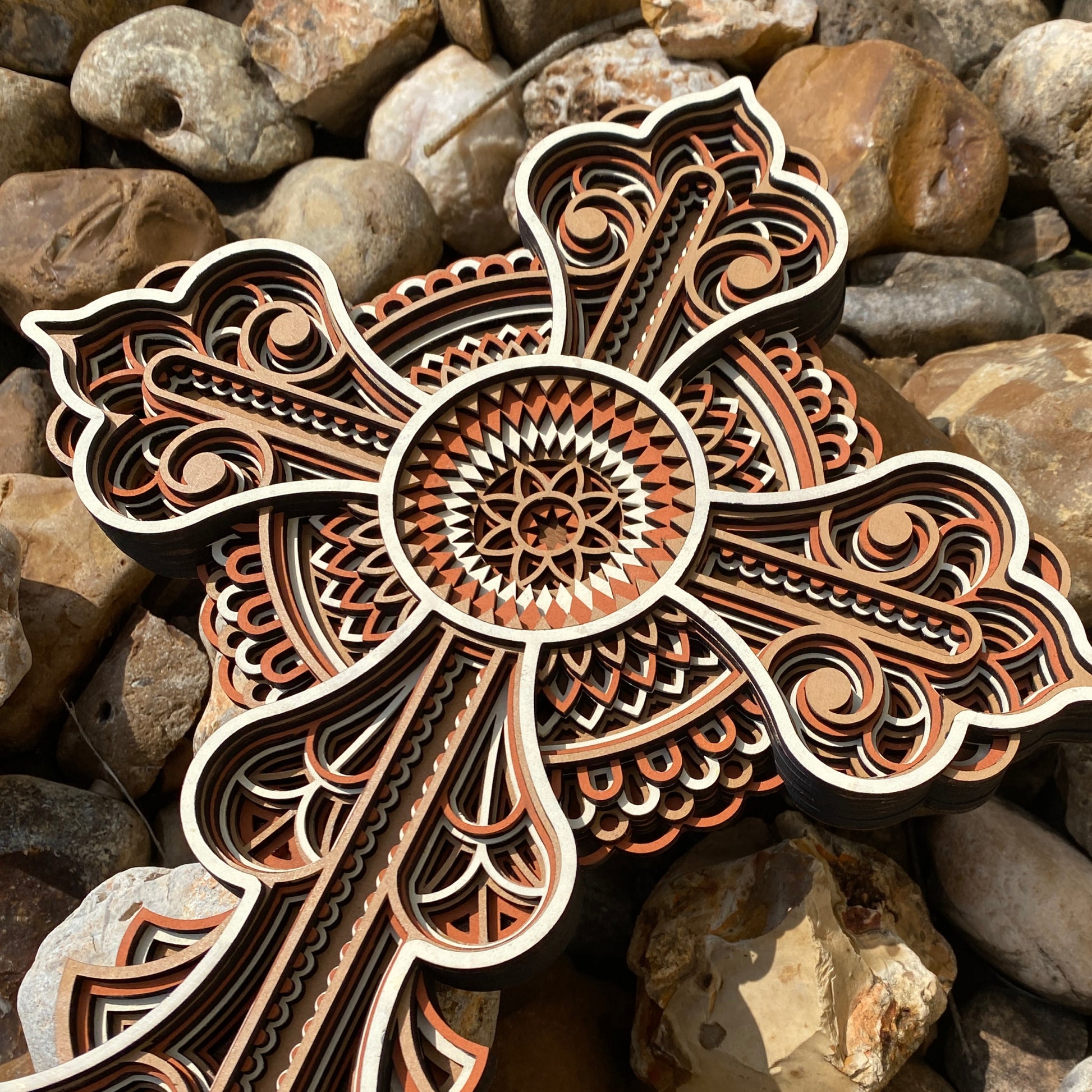 Decorative cross with intricate patterns on a background of stones